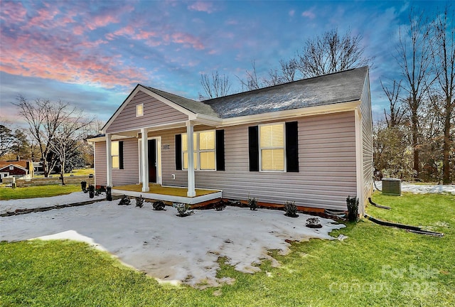 view of front of house with central AC unit, a lawn, and a porch