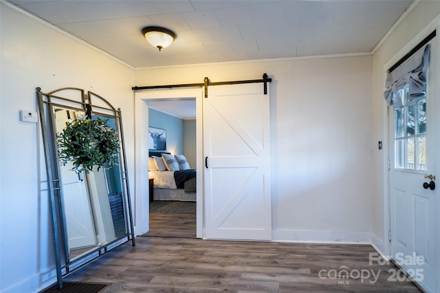 entrance foyer featuring a barn door, wood-type flooring, and ornamental molding