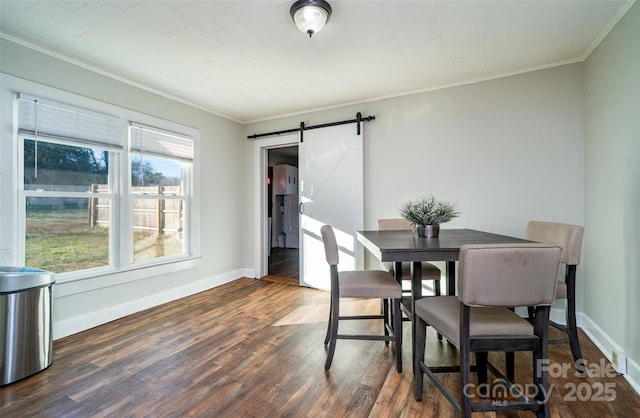 dining room featuring dark hardwood / wood-style flooring, a barn door, and ornamental molding