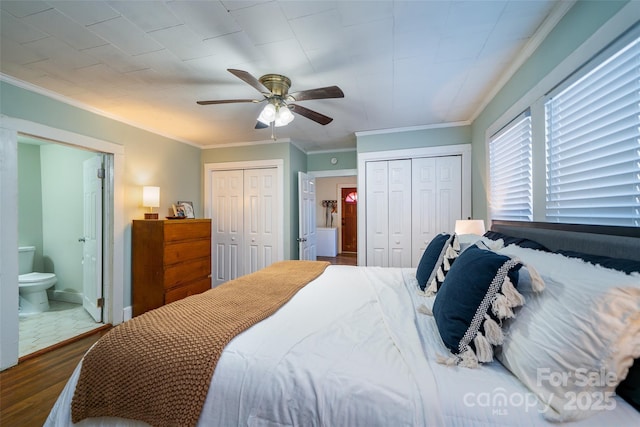 bedroom featuring dark wood-type flooring, ensuite bathroom, crown molding, and ceiling fan