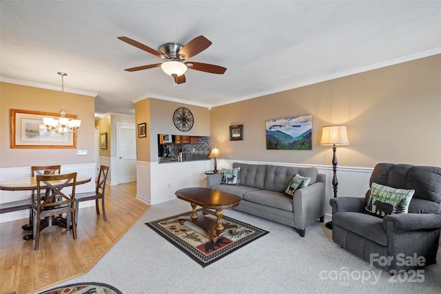 living room featuring light hardwood / wood-style floors, ceiling fan with notable chandelier, a textured ceiling, and ornamental molding