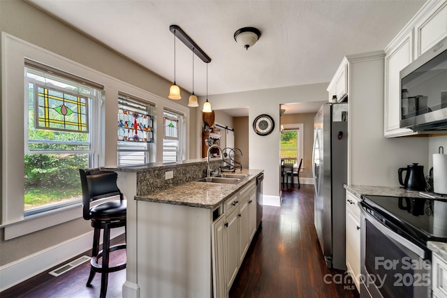 kitchen featuring a kitchen bar, sink, white cabinets, and appliances with stainless steel finishes