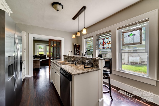 kitchen featuring light stone countertops, white cabinetry, hanging light fixtures, a kitchen breakfast bar, and stainless steel appliances