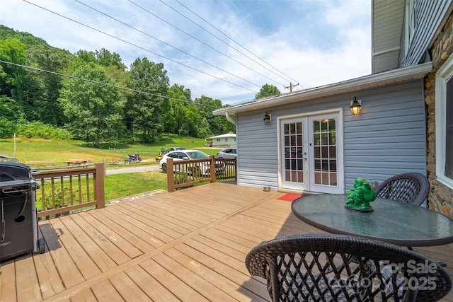 wooden terrace featuring a grill, a yard, and french doors