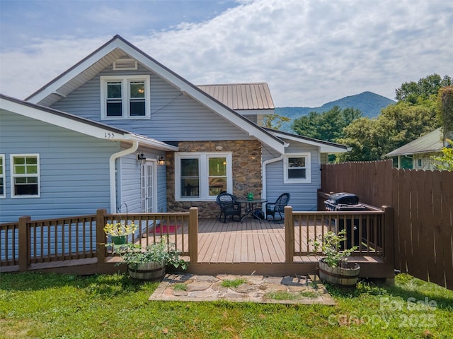 wooden deck with a mountain view and a lawn