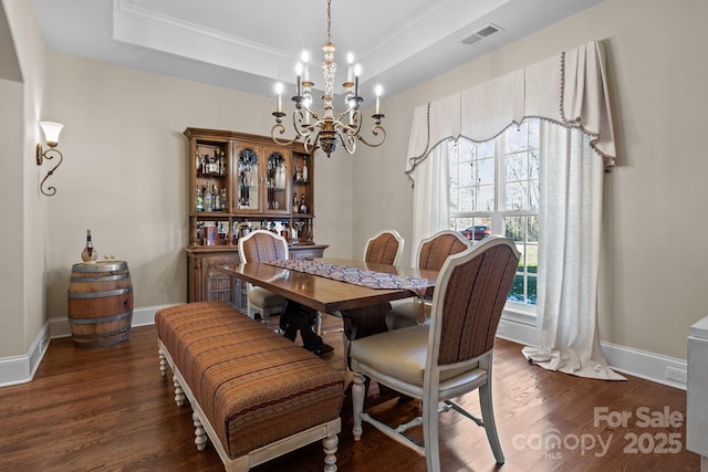 dining area with a raised ceiling, crown molding, a chandelier, and dark hardwood / wood-style flooring