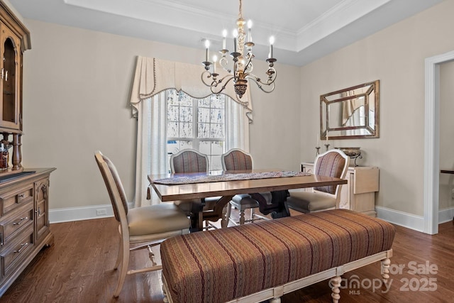 dining space featuring dark hardwood / wood-style flooring, ornamental molding, a chandelier, and a raised ceiling