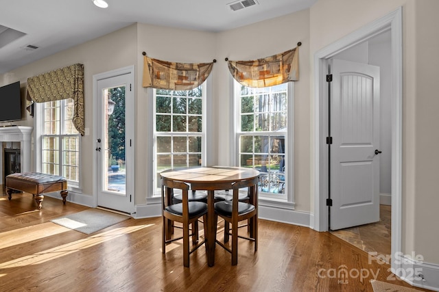 dining space with light wood-type flooring, a tile fireplace, and a wealth of natural light