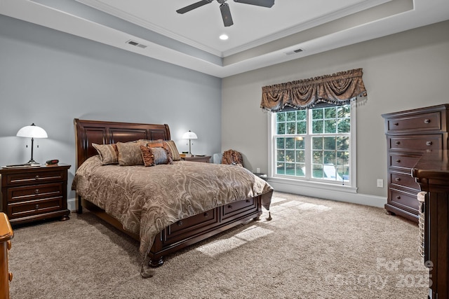 carpeted bedroom with ornamental molding, ceiling fan, and a raised ceiling