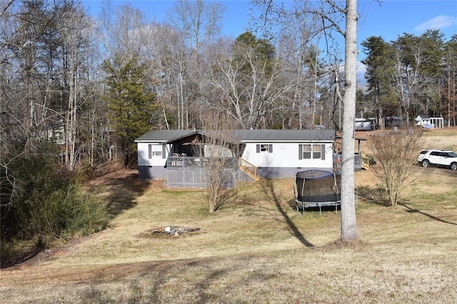 view of front facade with crawl space, a front yard, a trampoline, and metal roof