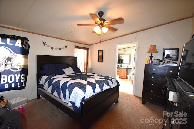 carpeted bedroom with ensuite bath, vaulted ceiling, crown molding, and a ceiling fan