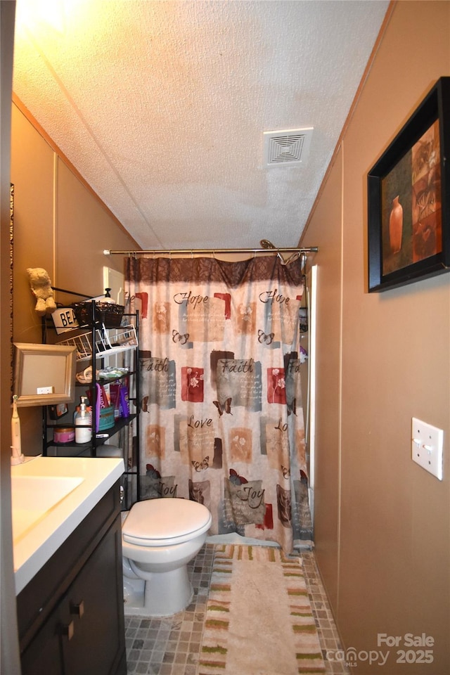 bathroom with curtained shower, a textured ceiling, toilet, and vanity