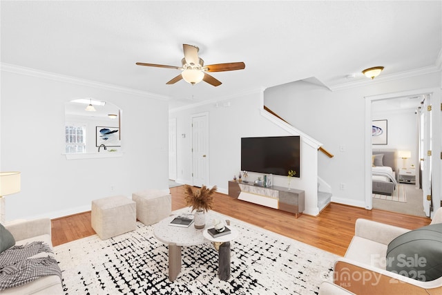 living room featuring hardwood / wood-style flooring, ornamental molding, and ceiling fan