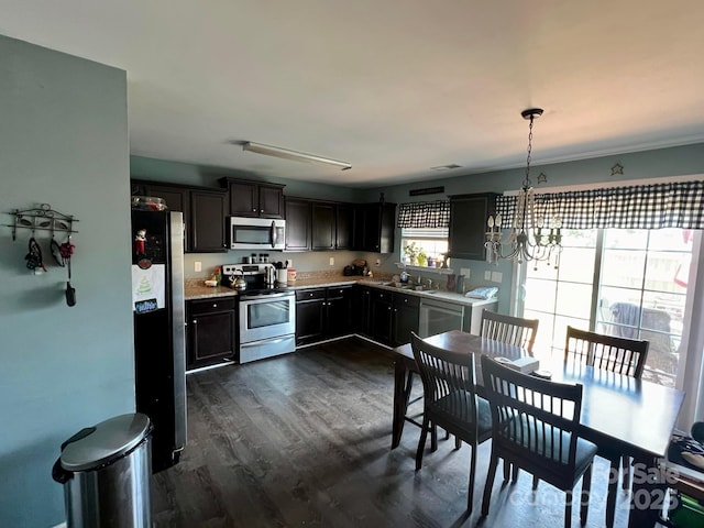 kitchen featuring an inviting chandelier, appliances with stainless steel finishes, dark wood-type flooring, pendant lighting, and dark brown cabinetry