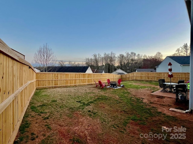 yard at dusk featuring an outdoor fire pit and a patio area