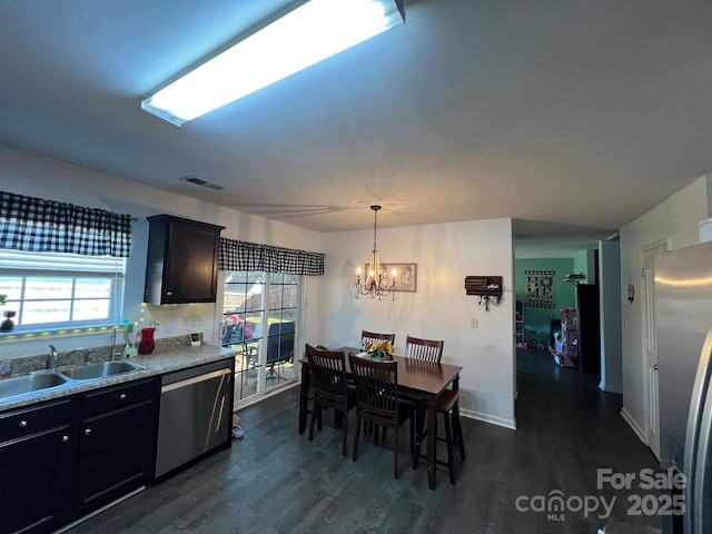 kitchen featuring light countertops, a sink, appliances with stainless steel finishes, dark wood-style floors, and an inviting chandelier