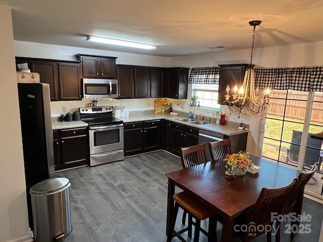 kitchen featuring light countertops, a chandelier, a sink, appliances with stainless steel finishes, and wood finished floors
