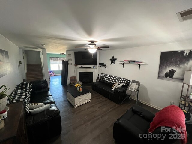 living area with stairway, a ceiling fan, a fireplace, wood finished floors, and visible vents