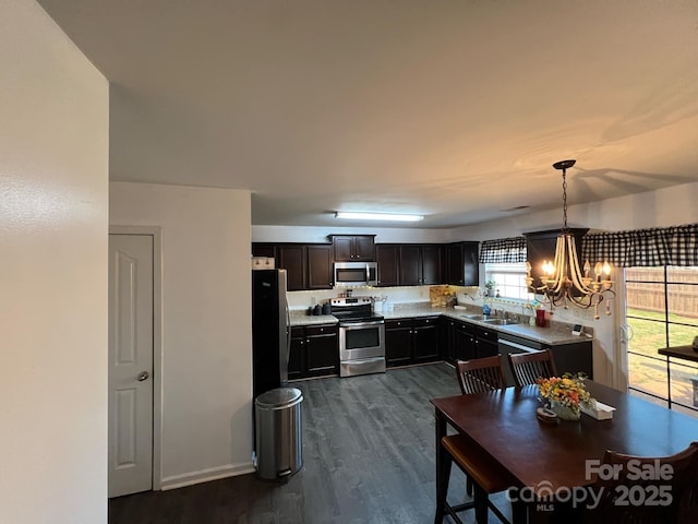 kitchen with a notable chandelier, light countertops, dark wood finished floors, stainless steel appliances, and decorative light fixtures