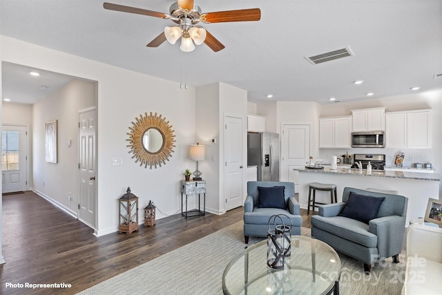 living room featuring ceiling fan and dark hardwood / wood-style floors