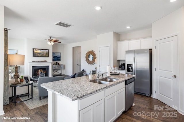 kitchen with sink, white cabinetry, a kitchen island with sink, dark wood-type flooring, and appliances with stainless steel finishes