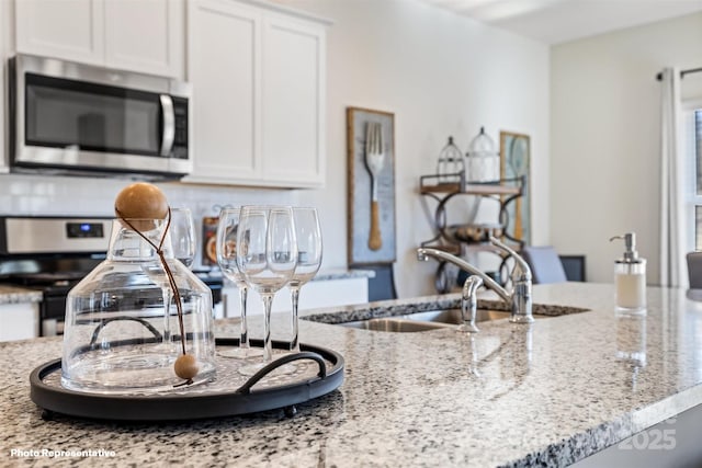 kitchen featuring decorative backsplash, sink, light stone countertops, appliances with stainless steel finishes, and white cabinets