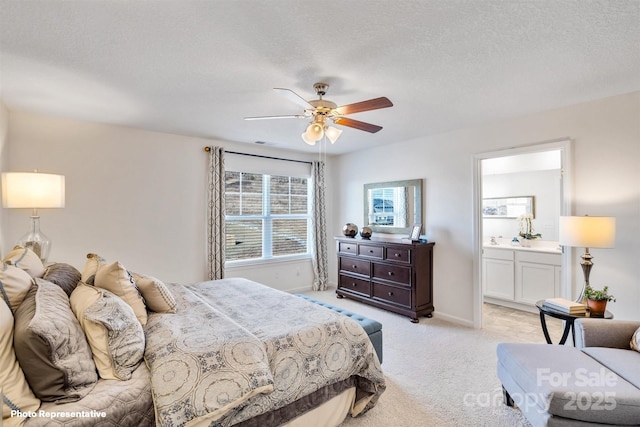 bedroom featuring ceiling fan, light colored carpet, a textured ceiling, and ensuite bathroom