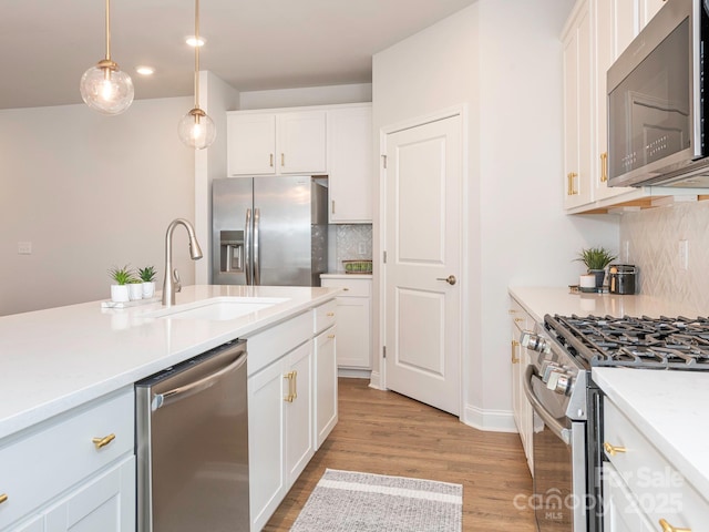 kitchen featuring stainless steel appliances, pendant lighting, white cabinetry, and sink