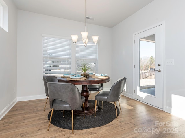 dining area featuring light wood-type flooring, a wealth of natural light, and an inviting chandelier