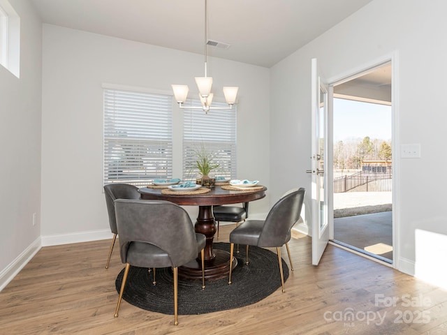 dining area with light hardwood / wood-style flooring and a notable chandelier