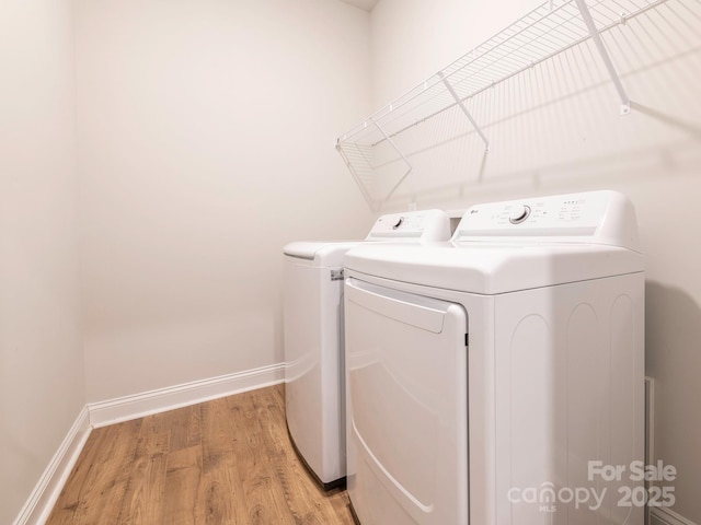 laundry area with washer and clothes dryer and light hardwood / wood-style floors