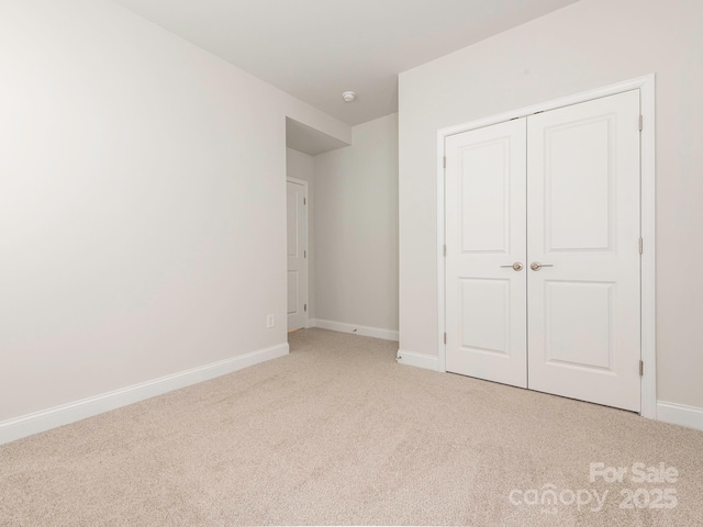 unfurnished bedroom with light colored carpet and a closet