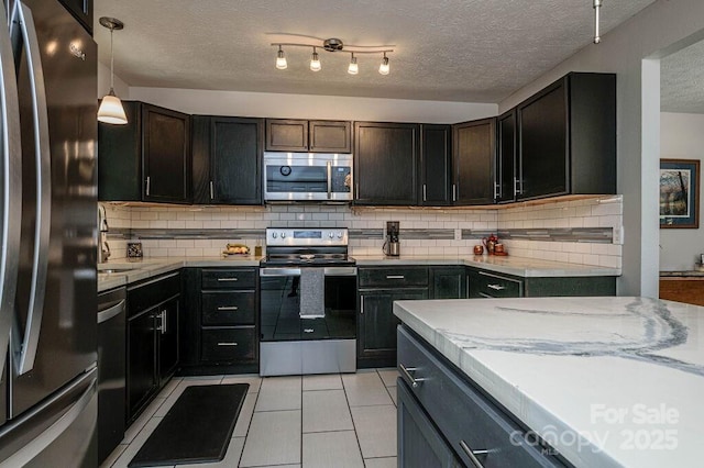 kitchen featuring light tile patterned floors, appliances with stainless steel finishes, decorative backsplash, a textured ceiling, and pendant lighting