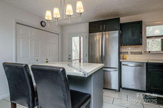 kitchen featuring a textured ceiling, a kitchen island, decorative light fixtures, stainless steel appliances, and a kitchen breakfast bar