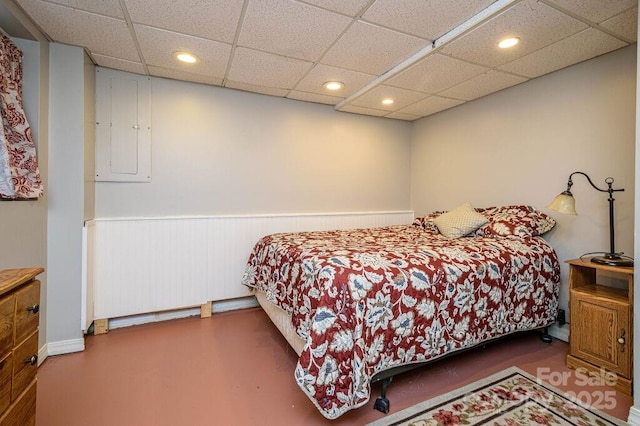 bedroom with a drop ceiling and electric panel