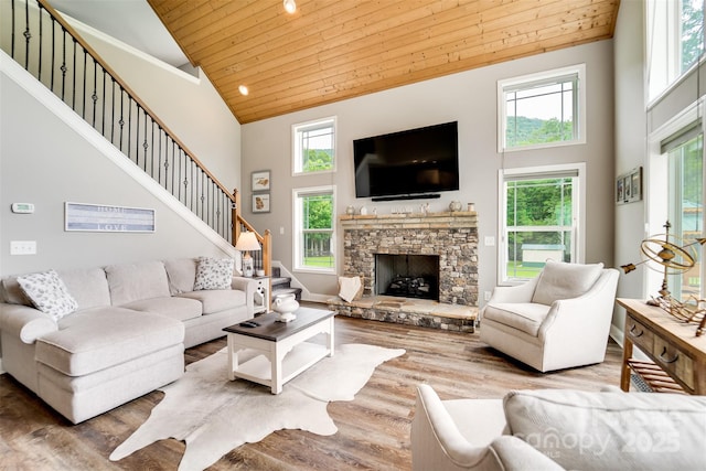 living room featuring high vaulted ceiling, wooden ceiling, wood-type flooring, and a stone fireplace