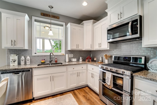 kitchen with light stone counters, sink, white cabinetry, and appliances with stainless steel finishes