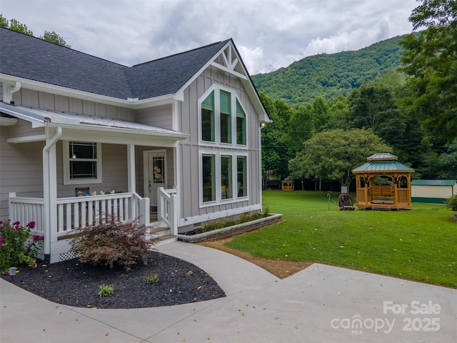 view of exterior entry featuring a mountain view and a lawn