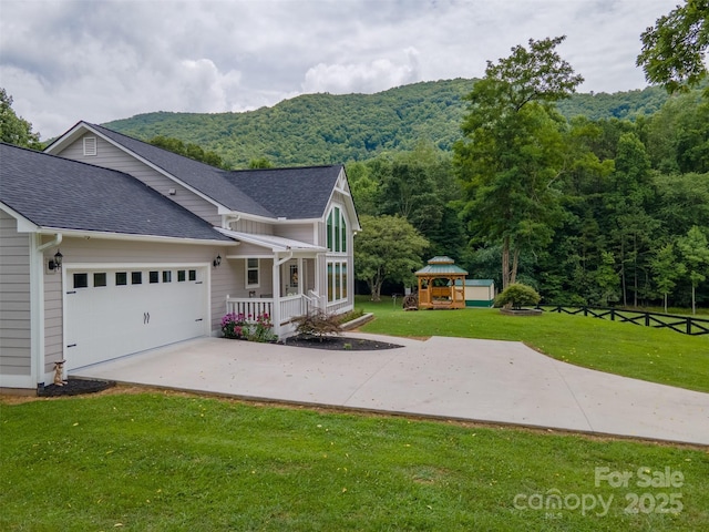 view of front of home featuring a mountain view, a front lawn, a garage, and a playground