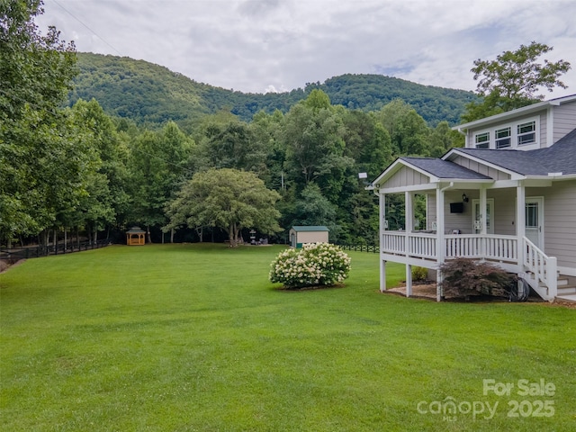 view of yard featuring a mountain view, a porch, and a storage unit