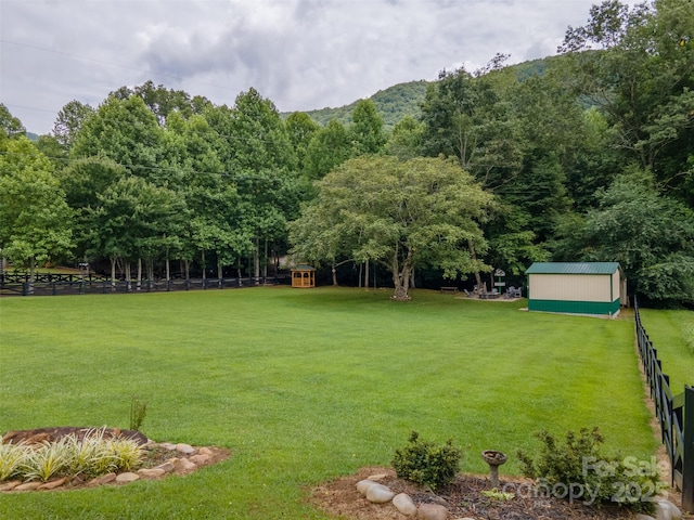 view of community with a mountain view, a lawn, and an outdoor structure