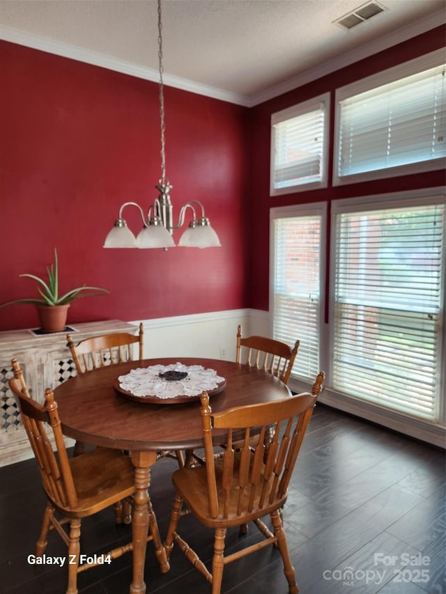 dining room with ornamental molding, dark hardwood / wood-style floors, and an inviting chandelier