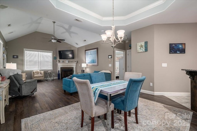 dining area with crown molding, a raised ceiling, dark hardwood / wood-style flooring, ceiling fan with notable chandelier, and lofted ceiling