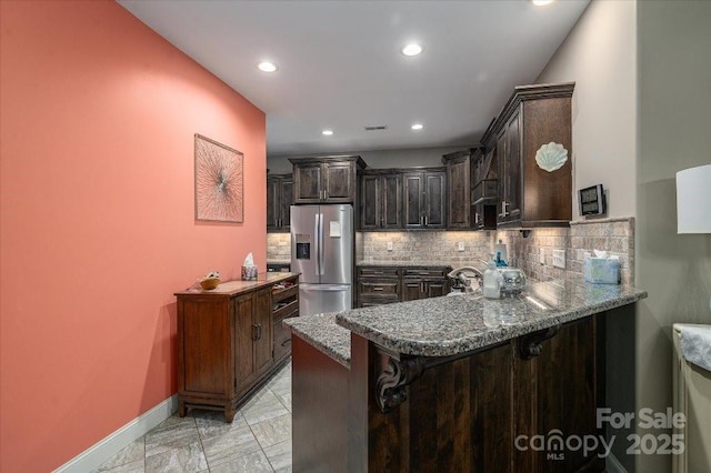 kitchen with a breakfast bar, backsplash, stainless steel fridge, and kitchen peninsula