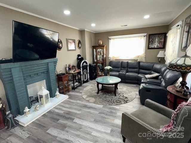 living room featuring a brick fireplace, wood-type flooring, and ornamental molding