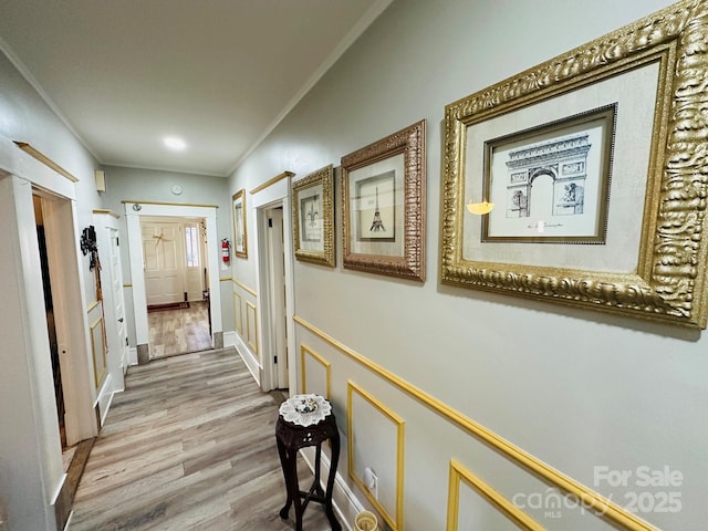 hallway with wood-type flooring and ornamental molding