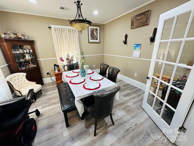 dining room with ornamental molding and light hardwood / wood-style flooring