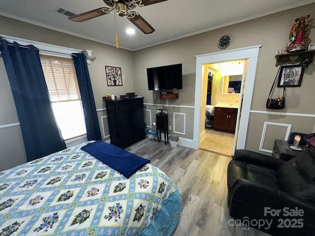 bedroom featuring ceiling fan, connected bathroom, ornamental molding, and light wood-type flooring