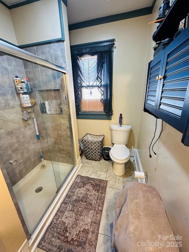 bathroom featuring toilet, a shower with door, ornamental molding, and tile patterned flooring