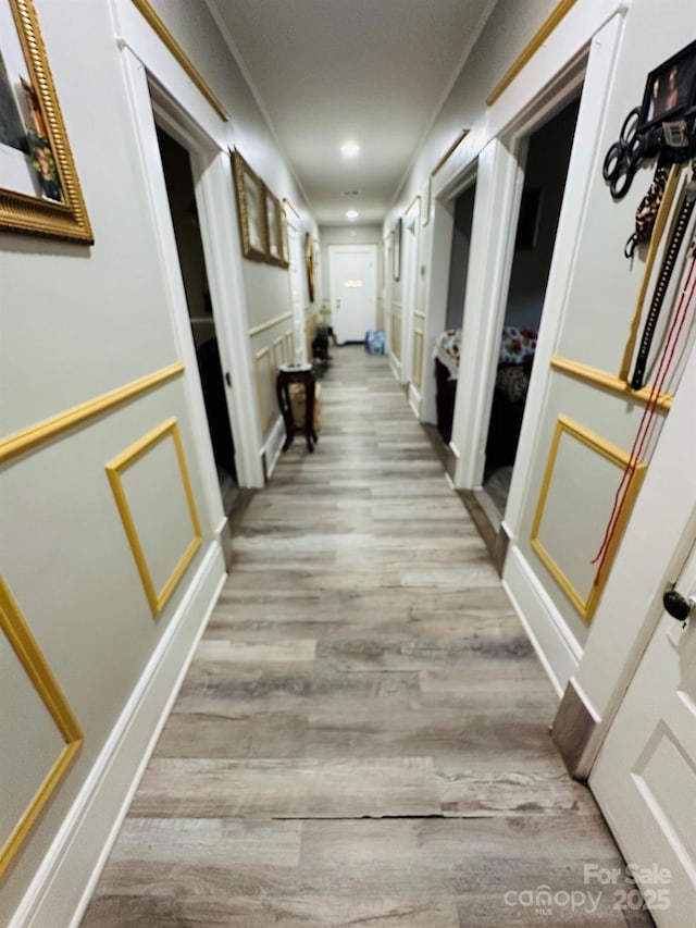 corridor featuring ornamental molding and light hardwood / wood-style flooring